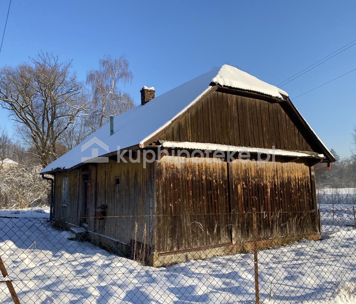 Drewniany dom jednorodzinny na ogrodzonej działce zimą, sprzedaż wierzytelności hipotecznej