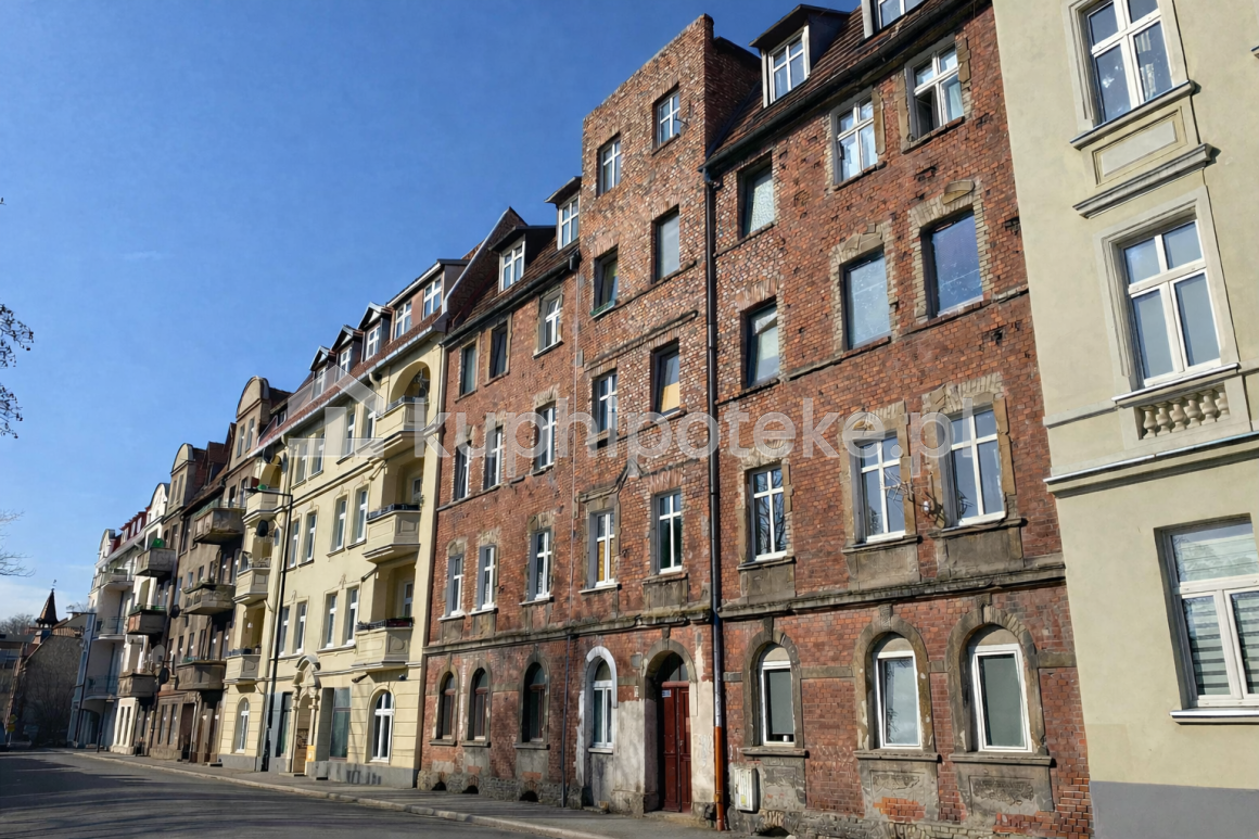 Kamienica z czerwonej cegły przy ulicy miejskiej, sprzedaż wierzytelności hipotecznej